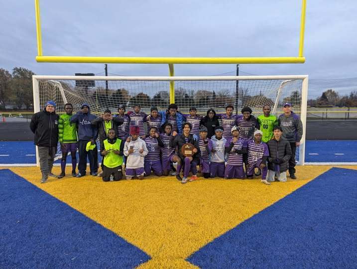 Lafayette High School Boys Soccer team posign in front of goal with trophy