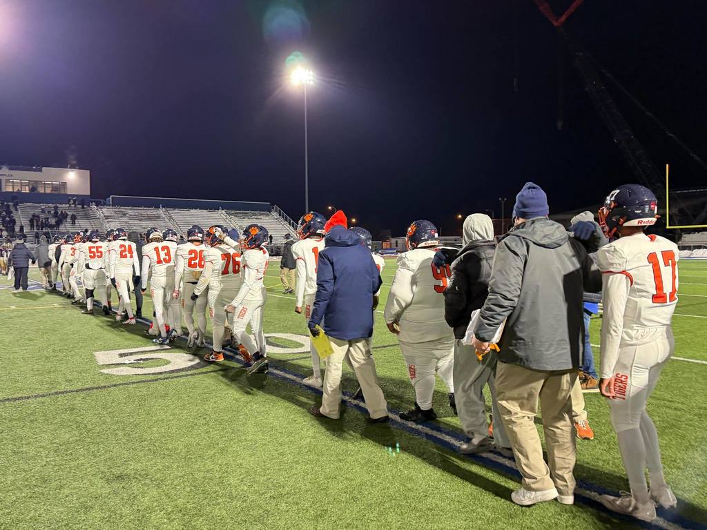 Bennett Tigers Football Team Walking in a single file line on the 50 yard line
