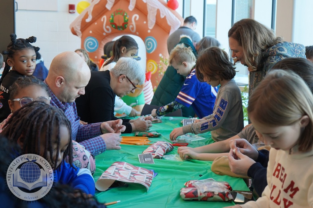 Parents, teachers and students warpping gifts at a table