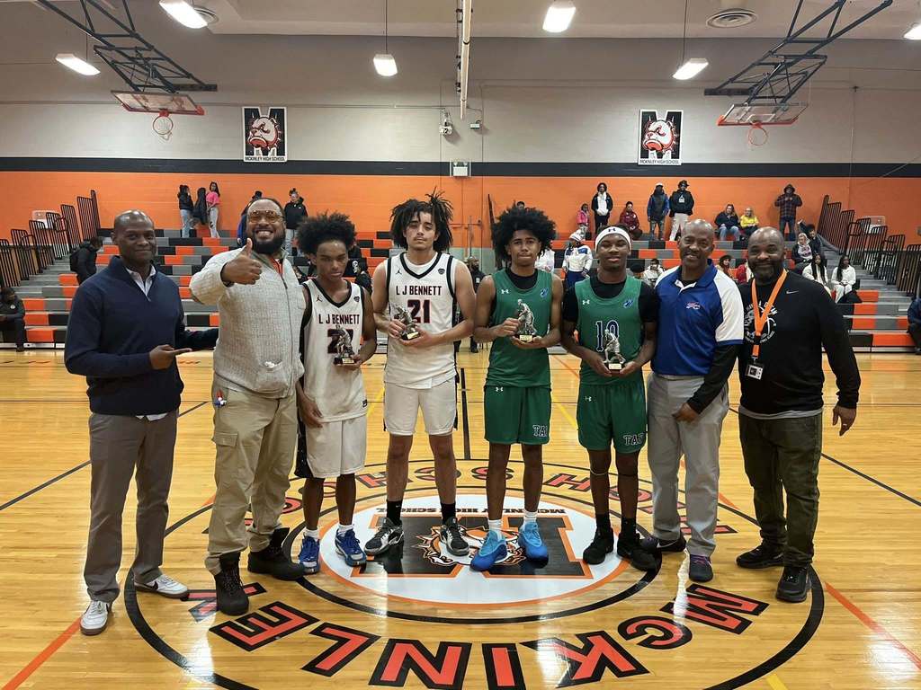 High School basketball players and coaches posing with Trophies