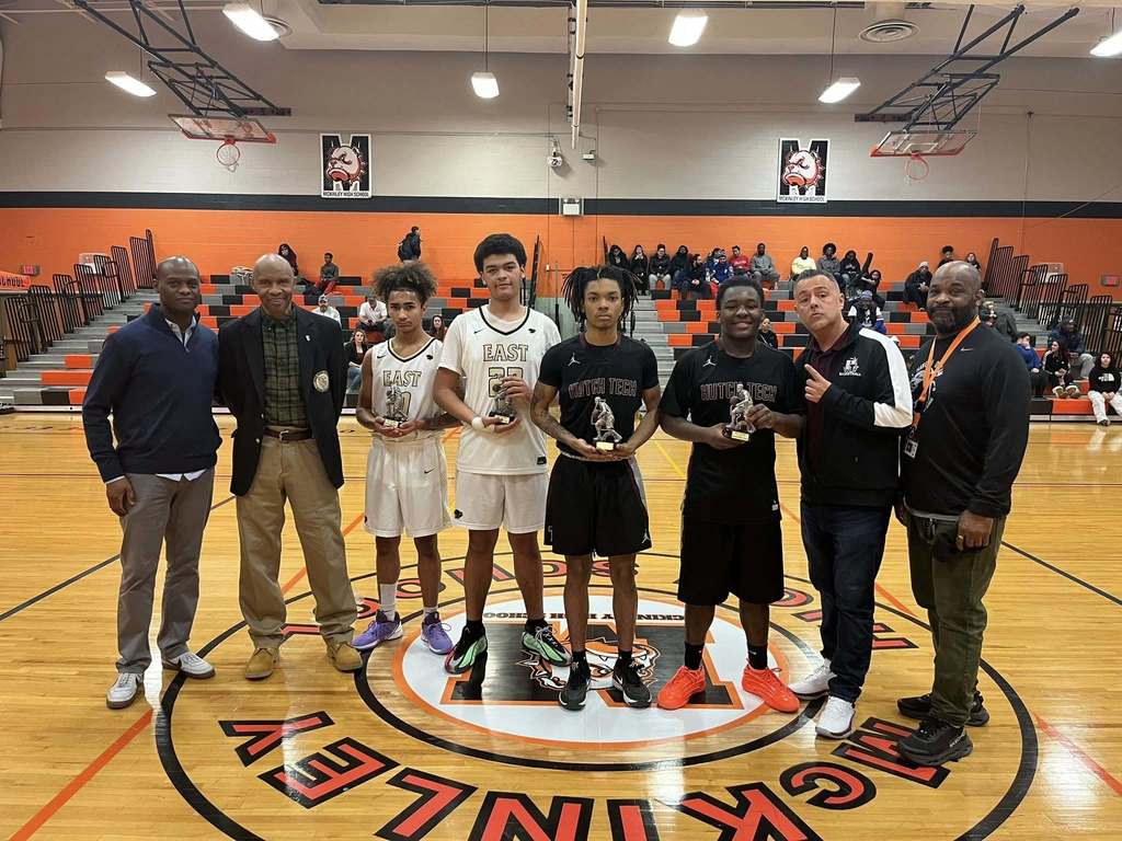High School basketball players and coaches posing with Trophies
