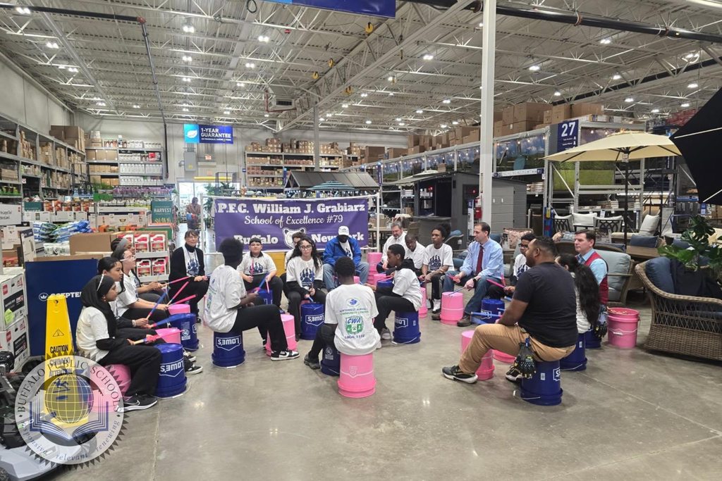 Students in a drum circle playing on buckets at Lowes Department Store
