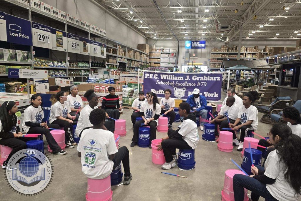 Students in a drum circle playing on buckets at Lowes Department Store