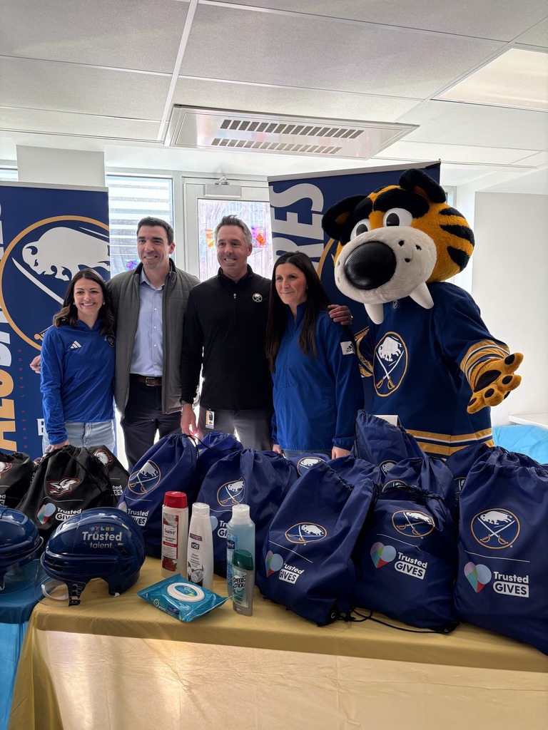 Adults with Sabretooth Sabres Mascot standing in front of doated bags