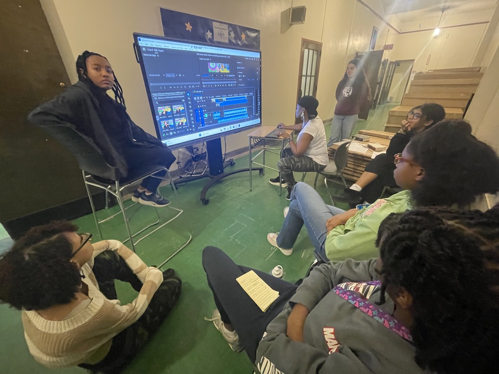 A group of student in front of a  display board editing video as a  group.
