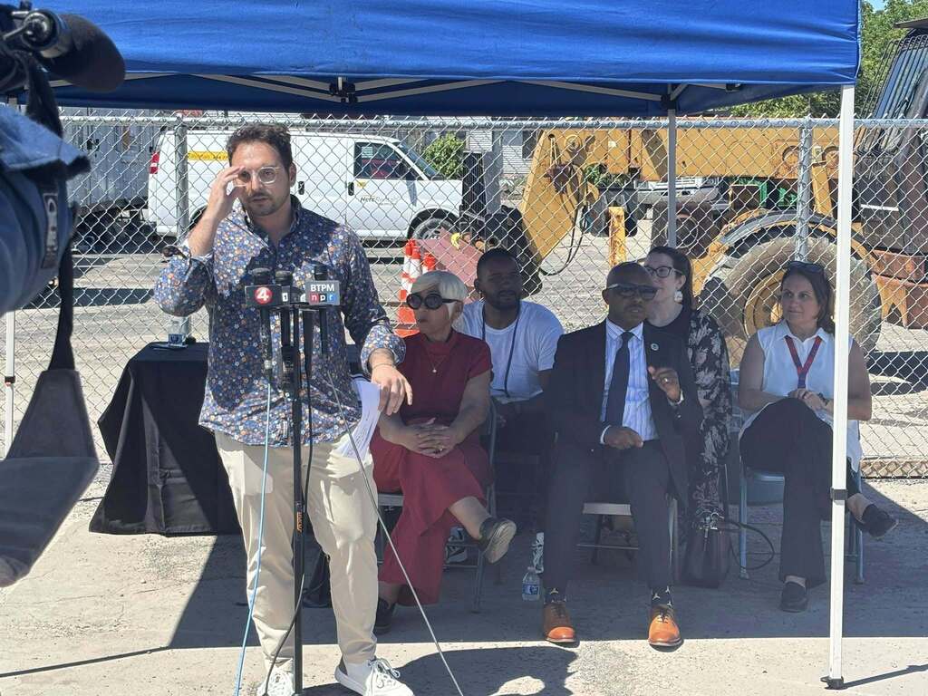 Man Speaking under a tent on news microphones