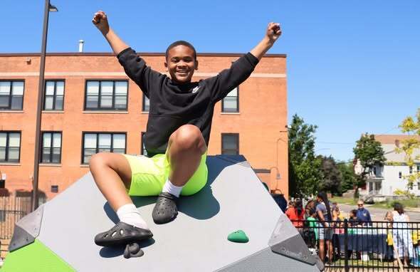 Students and adults at a playground opening ribbon cutting and enjoying playground.