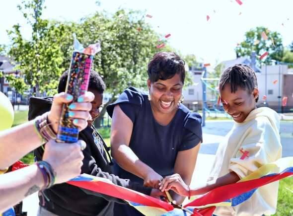 Students and adults at a playground opening ribbon cutting and enjoying playground.