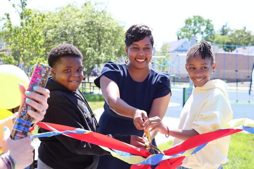Students and adults at a playground opening ribbon cutting and enjoying playground.
