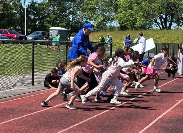 People commencing a track ceremony presenting check and kids at track. 
