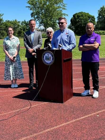 People commencing a track ceremony presenting check and kids at track. 