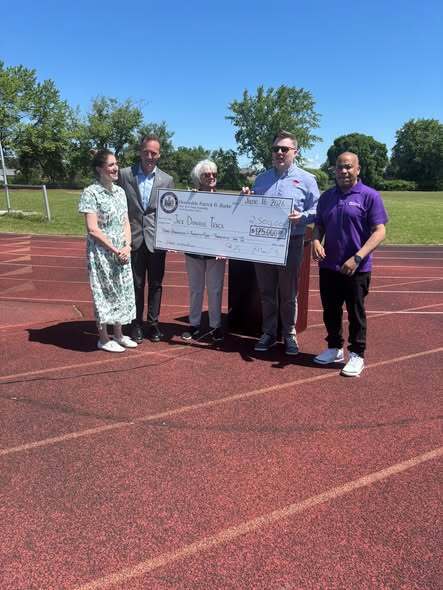 People commencing a track ceremony presenting check and kids at track. 