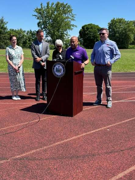 People commencing a track ceremony presenting check and kids at track. 