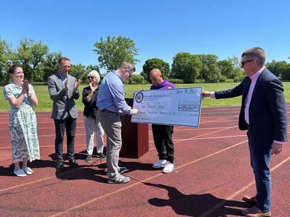 People commencing a track ceremony presenting check and kids at track. 