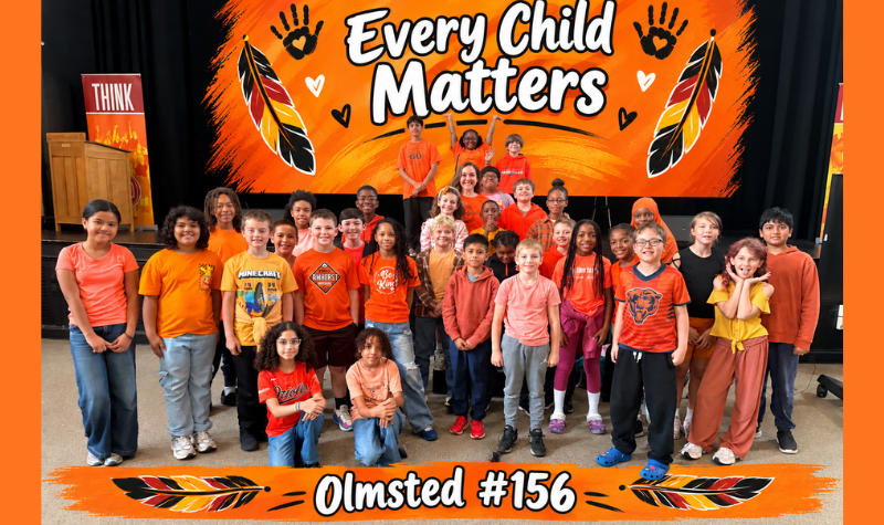 Students from 156 in a group in Orange shirts located in auditorium