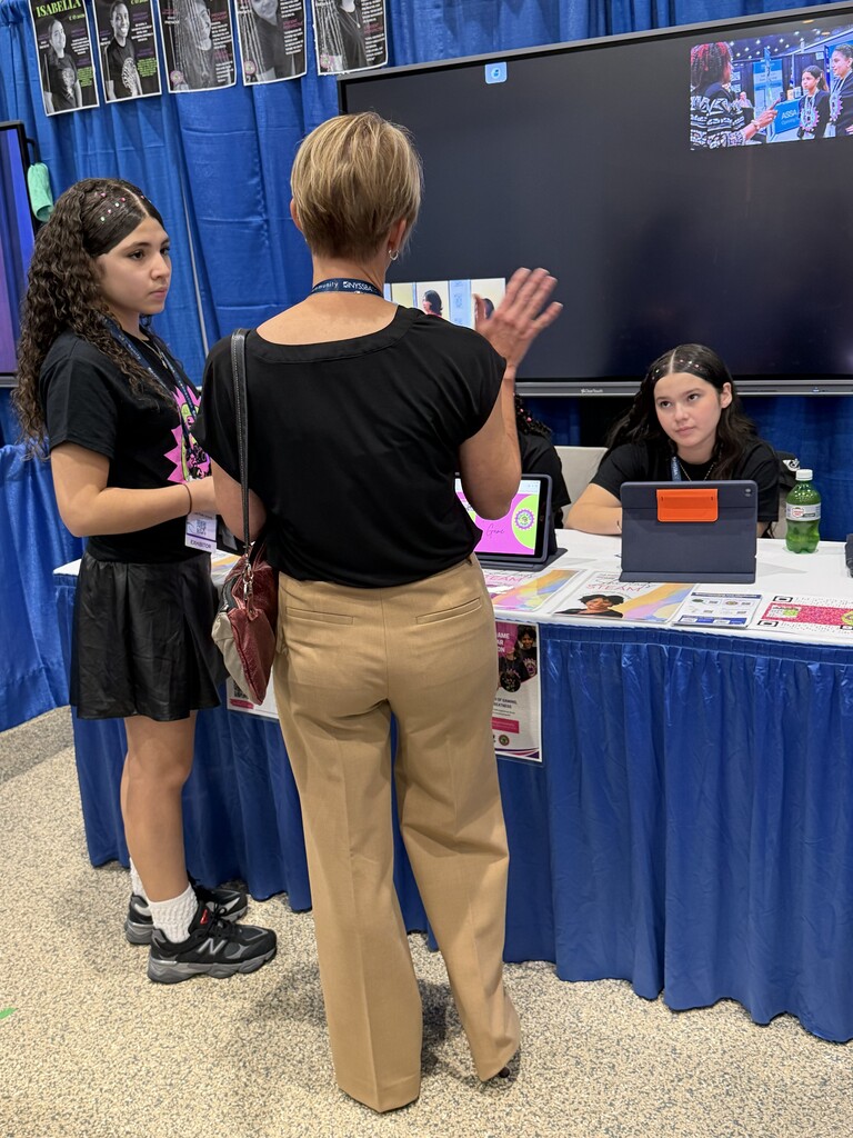 female student standing beside woman and another female student sitting at a table