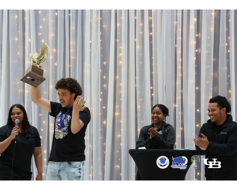 Students holding trophy on stage
