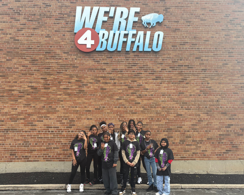 STLP outside WIVB Building under a sign that says "We're 4 Buffalo"