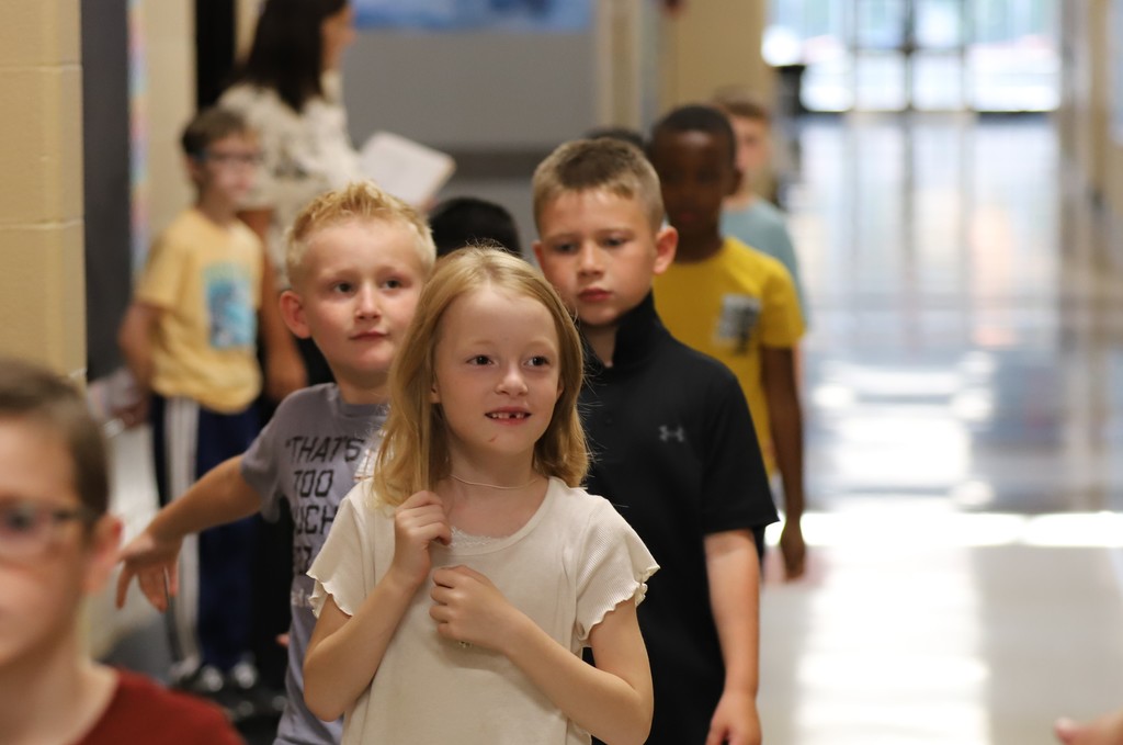 Student smiling and holding hair in hallway