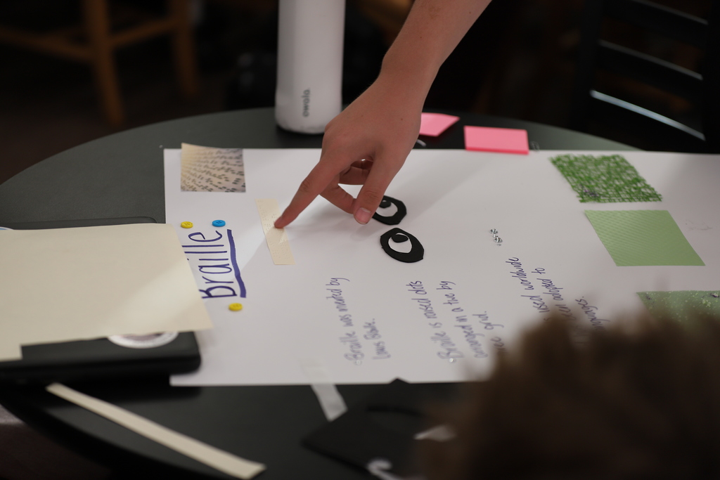 Student touching braille on a poster