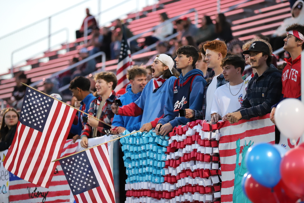 Students Cheering at a Football Game with Red, White, and Blue decorations