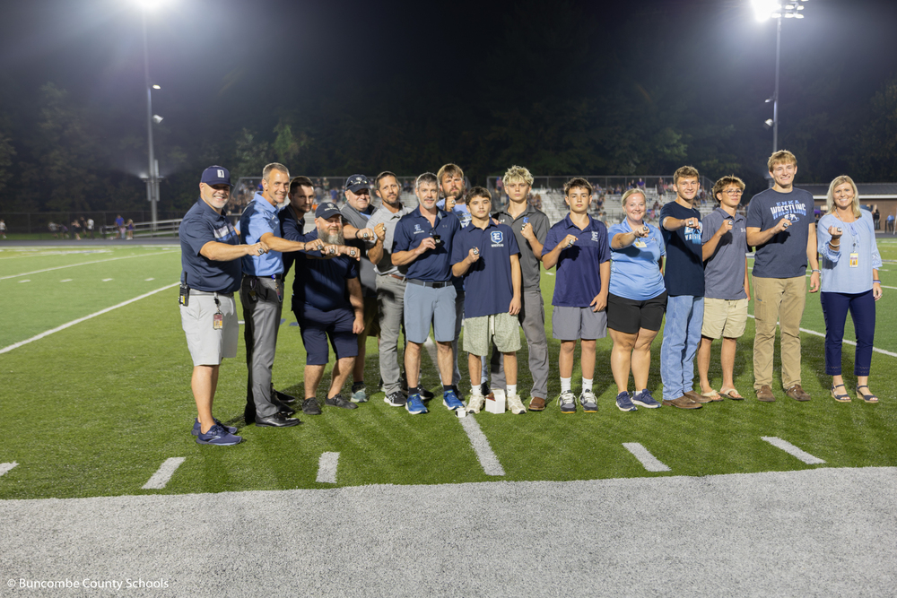 The wrestling team, coaches, and principals showing off the new state championship rings. 