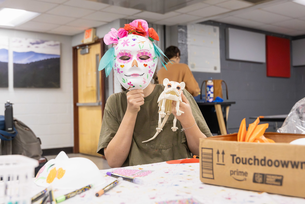 A student holds up an animal skeleton and a sugar skull.