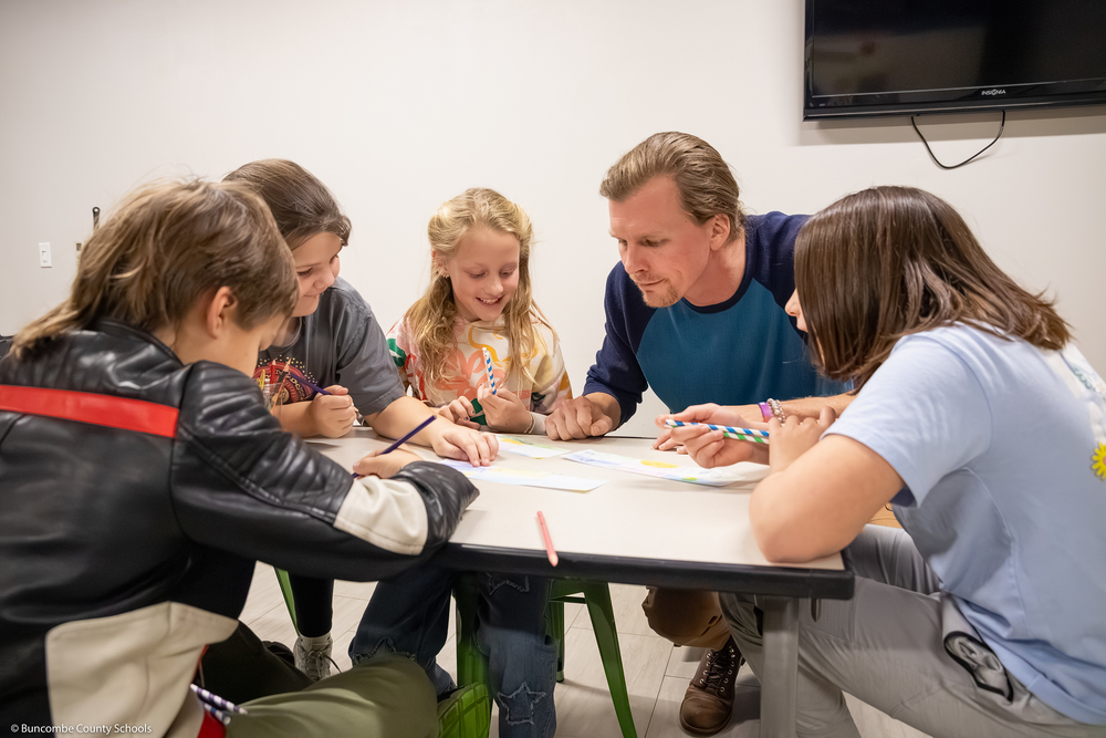 Students and Mr. Wescott work on a scrolling art project.