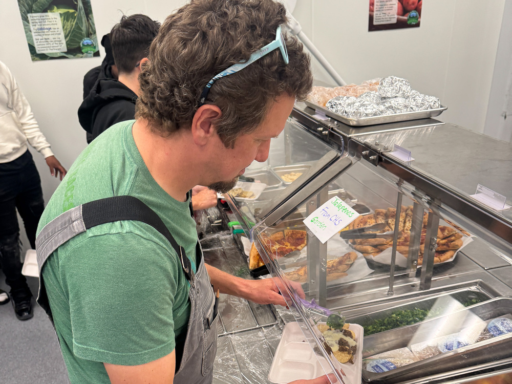 Mr. Foote puts peppers on his tray from the school lunch line.