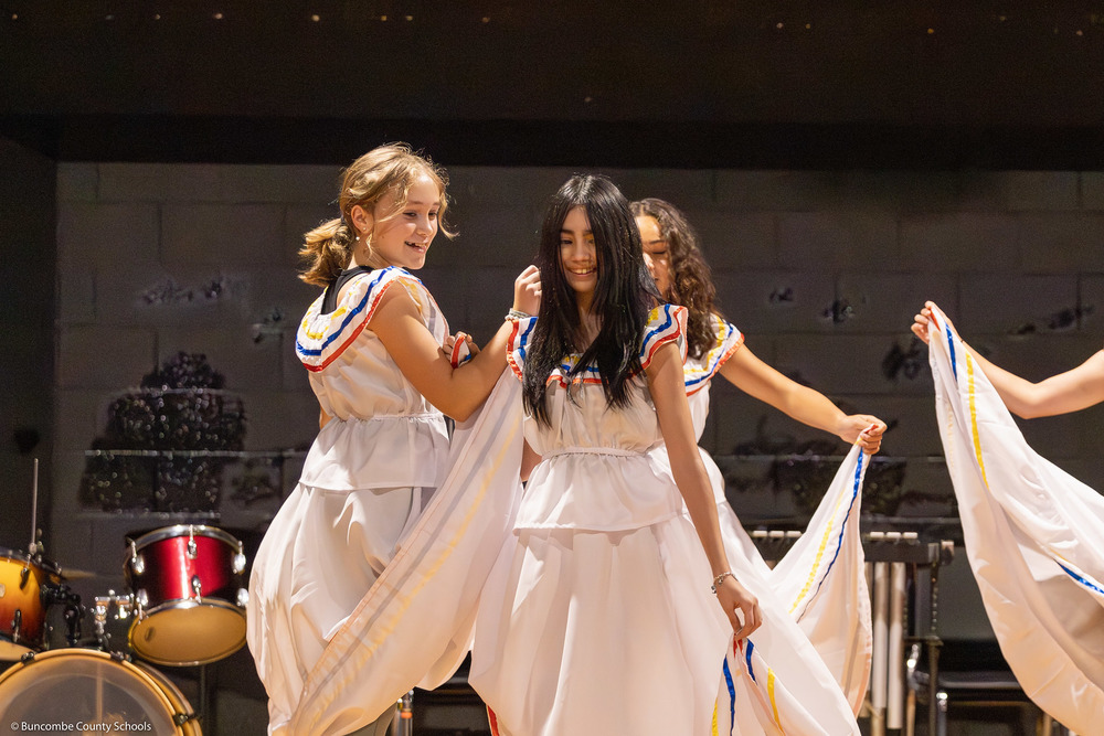 Students smile as they dance Cumbia.