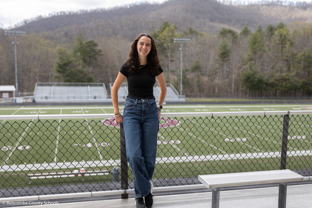 Jordan standing at the top of the warhorse football stadium. The mountains and football field are in the background. 