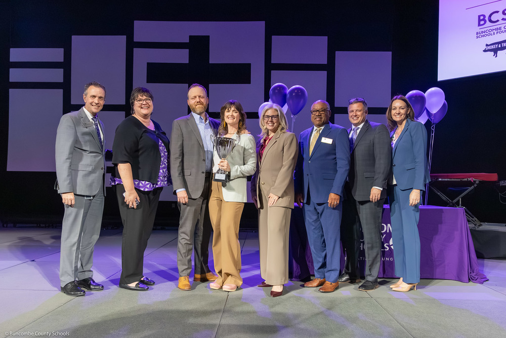 Ms. Shreve holds her trophy on stage. She is surrounded by BCS administrators.