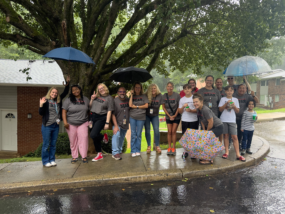 Johnston Elementary teachers and students posing together in the rain for a group photo. 
