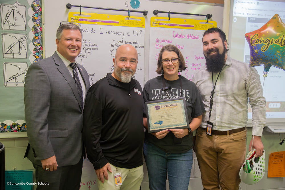 Mr. Cody, Mr. Yontz, Mrs. Stowe, and Mr. Arvey stand posing for a photo in a classroom. Mrs. Stowe is holding a certificate. Mr. Arvey is holding a balloon. 