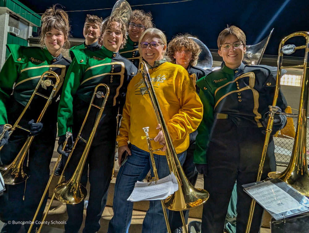 Dr. Reed holding her trombone surrounded by members of the Reynolds band in their uniforms, holding their trombones.