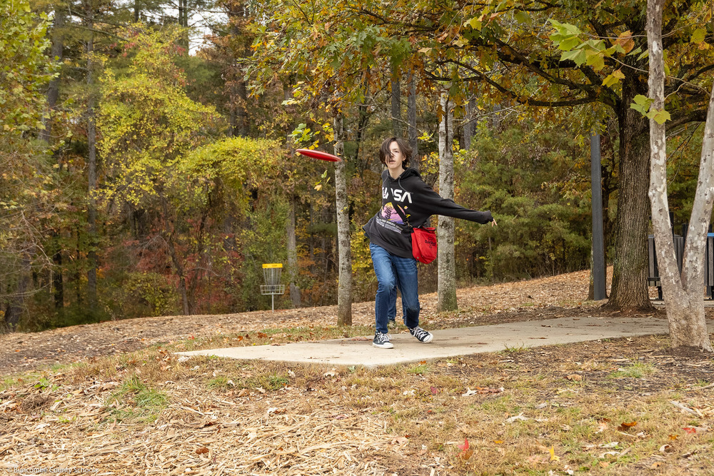A student launches a disc off the tee platform.