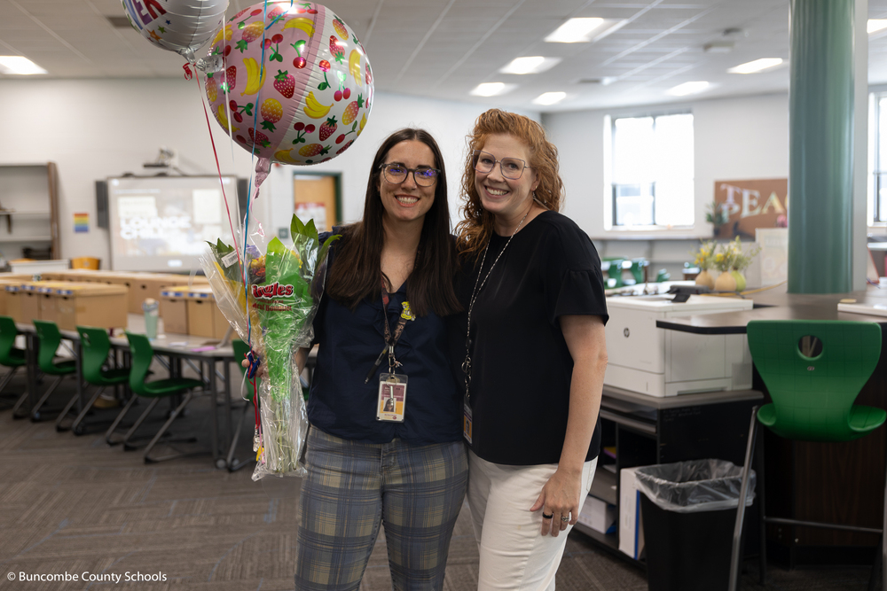 Alicia Luke holding flowers and a balloons and standing with Lila Morel. 