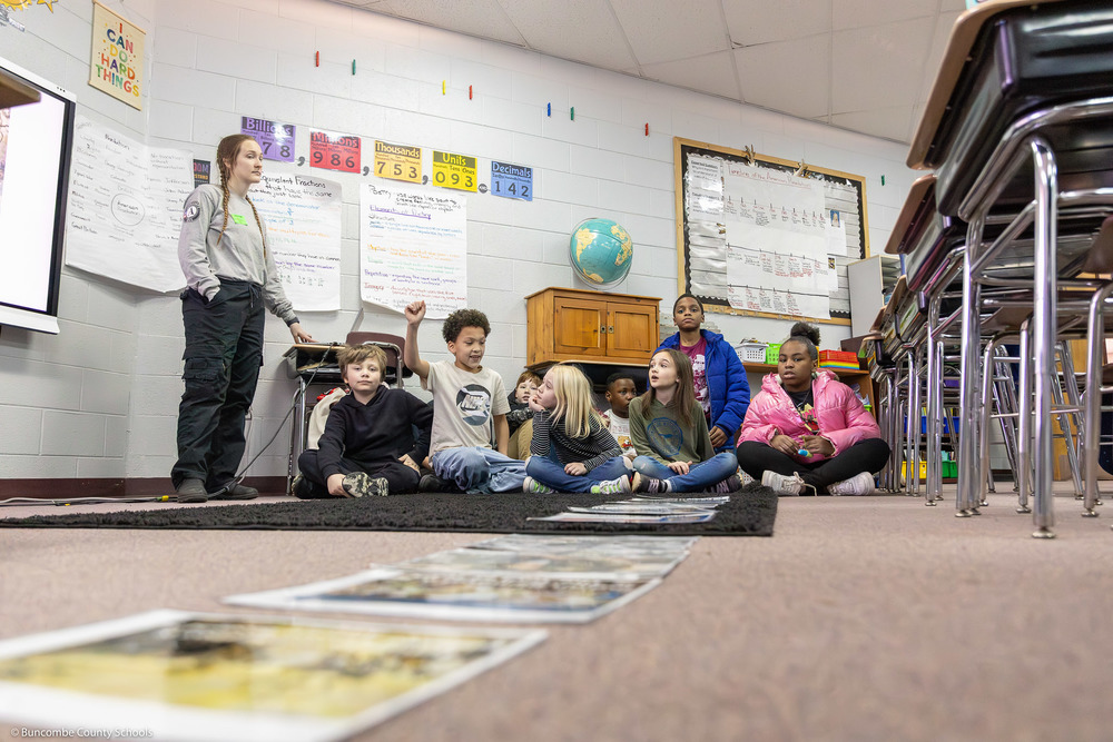 Oakley students sit on the floor in front of laminated sheets of paper.