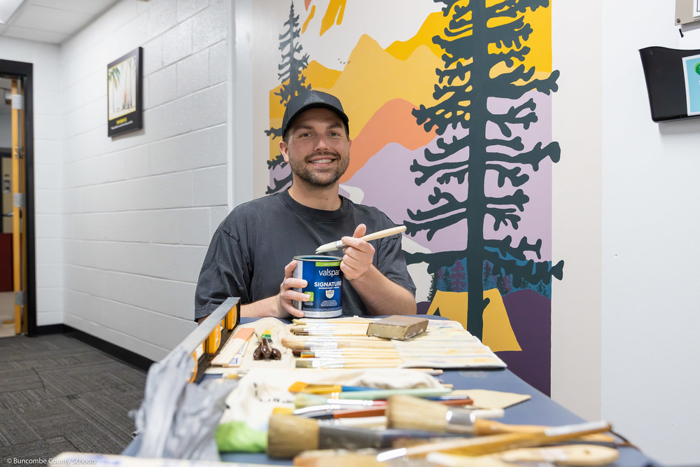 Robbie Edsell poses with his supplies in front of the new mural.