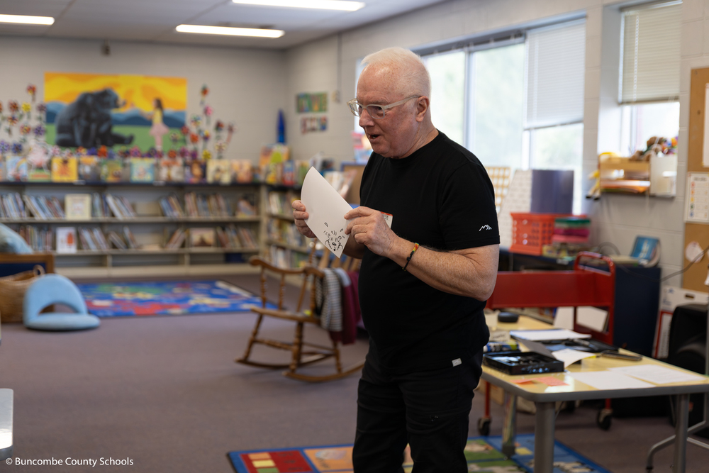 Artist Jim Jenkins holding a drawing he drew as an example for students to see. 