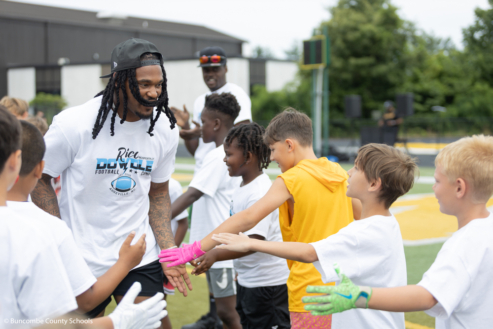 Rico Dowdle running by kids and giving them a high five. 