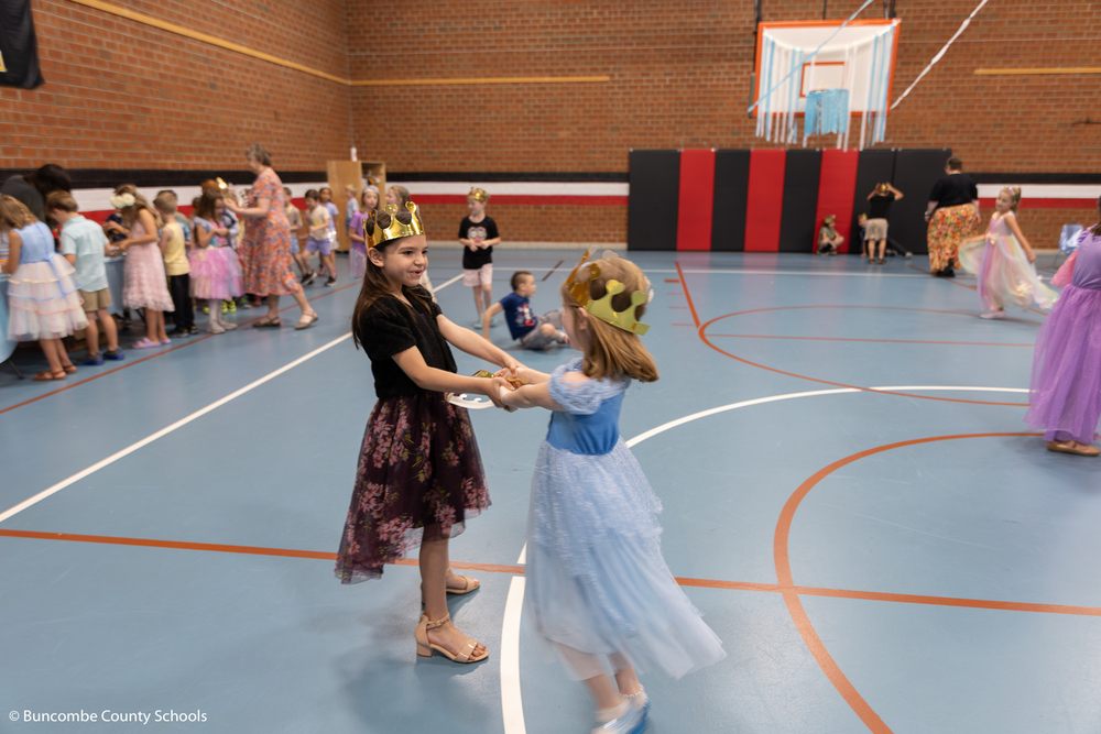 Two girls spinning each other around the gym. 