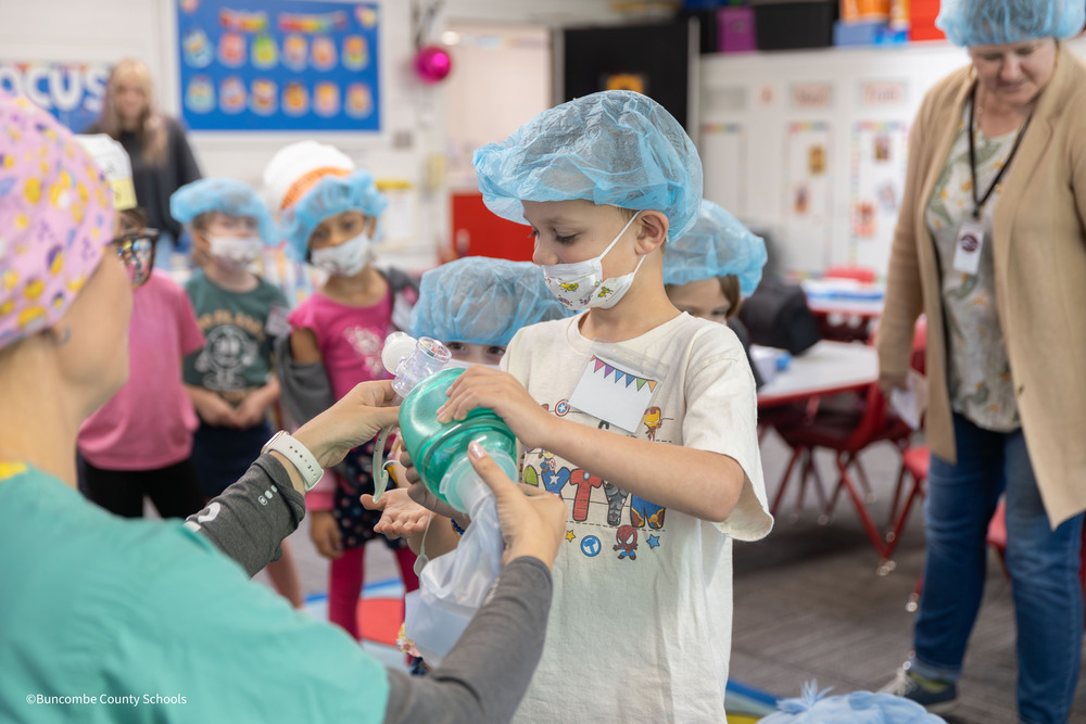 Student uses an AMBU bag to blow air onto his hand