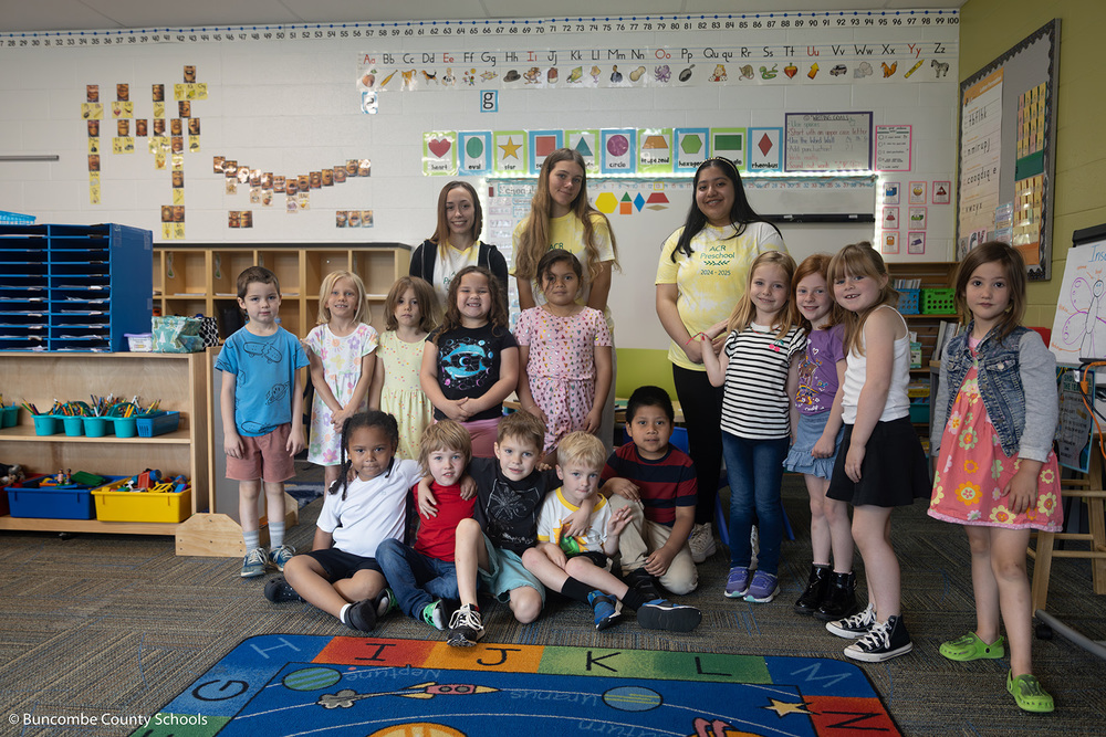 High school students and Kindergarteners standing together for a group photo. 