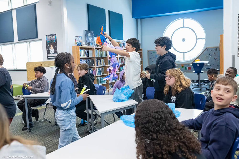 Students trade "dragons" made of paper rings, with a hustle and bustle of tables.