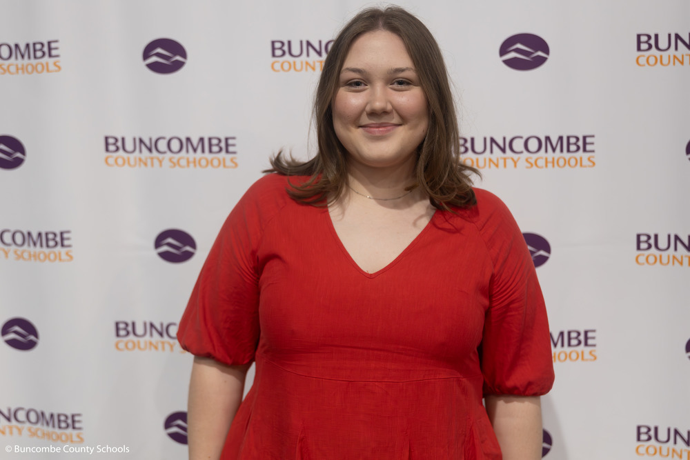 Isabella Geier poses in front of a Buncombe County Schools banner