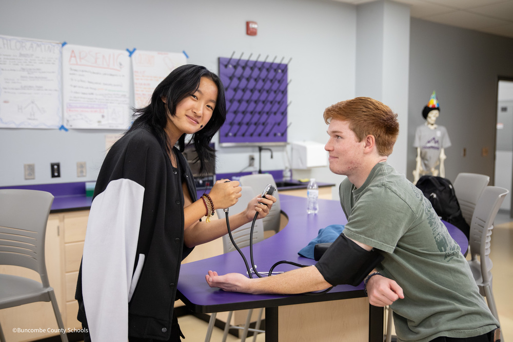 A student holds a blood pressure monitor as she prepares to take the blood pressure of another student