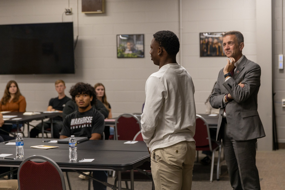 Dr. Jackson stands next to a student speaking to his peers at the Student Advisory Council meeting