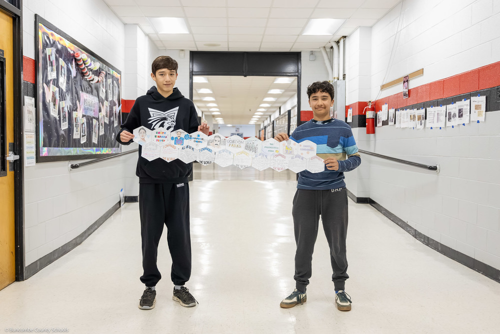 Two students hold part of the quilt in a school hallway.
