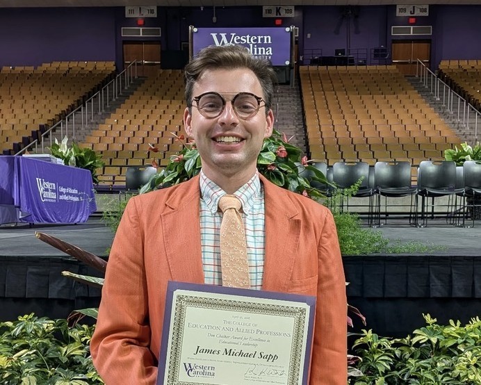 Mr. Sapp stands in the arena at WCU holding his certificate.